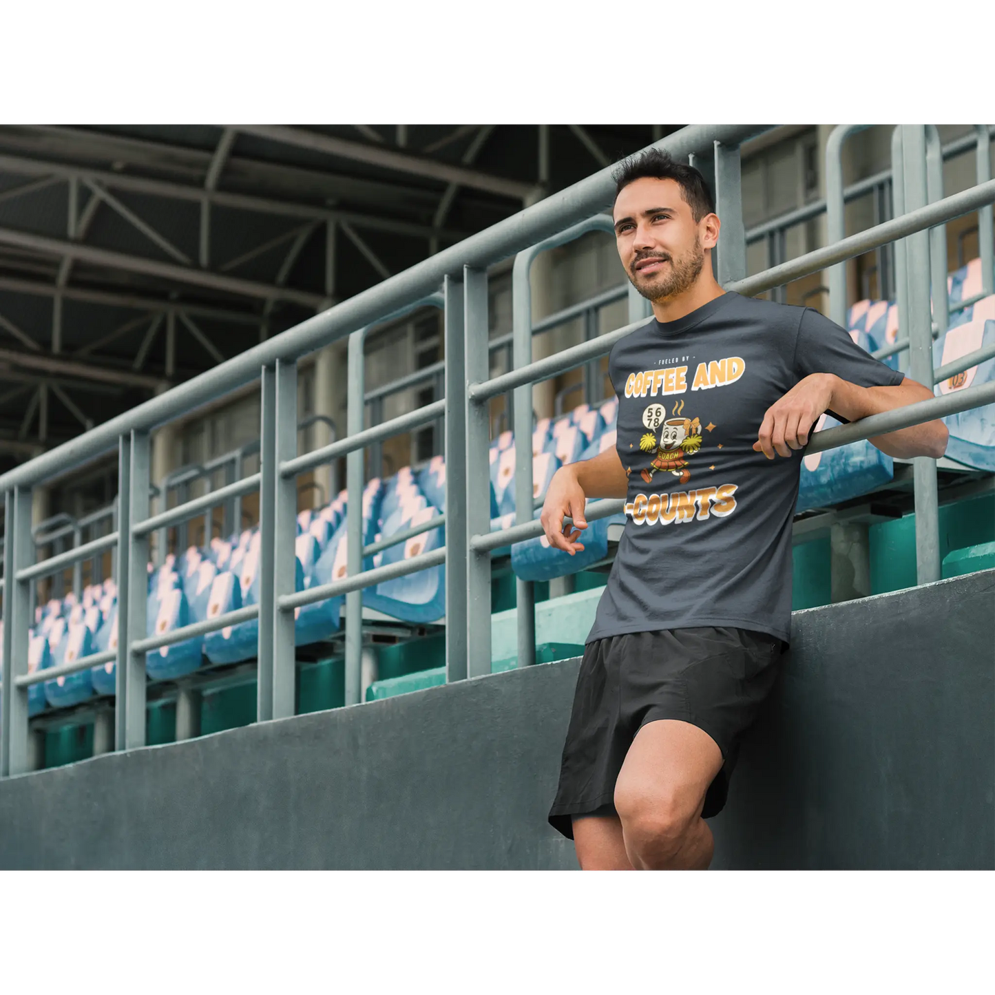 Male Cheerleading coach wearing a black t-shirt with a cheerleading graphic design on a football field