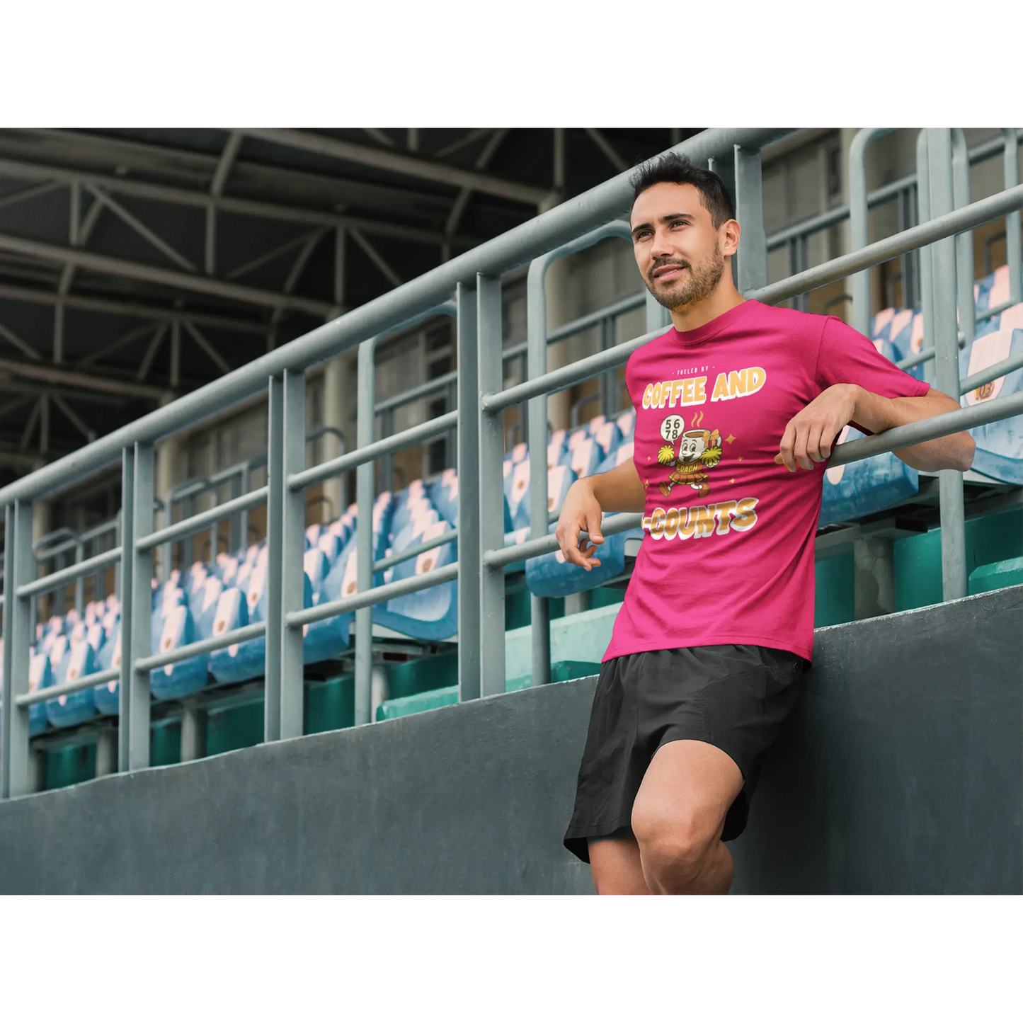 Male Cheerleading coach wearing a red t-shirt with a cheerleading graphic design in a football stand
