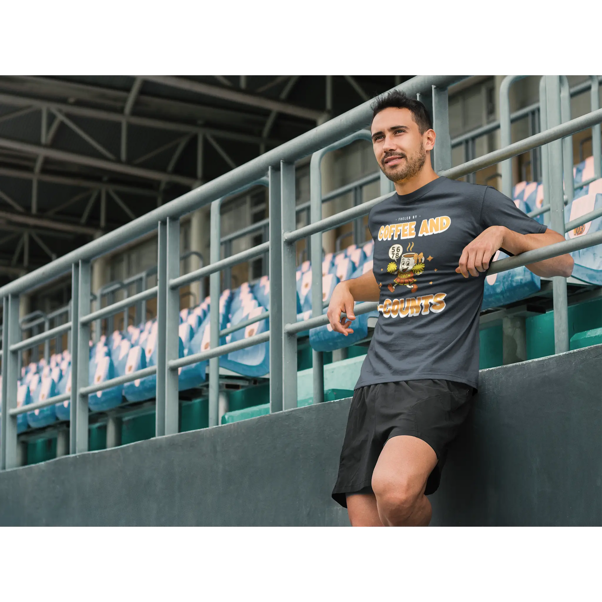 Male Cheerleading coach wearing a black t-shirt with a cheerleading graphic design on a football field