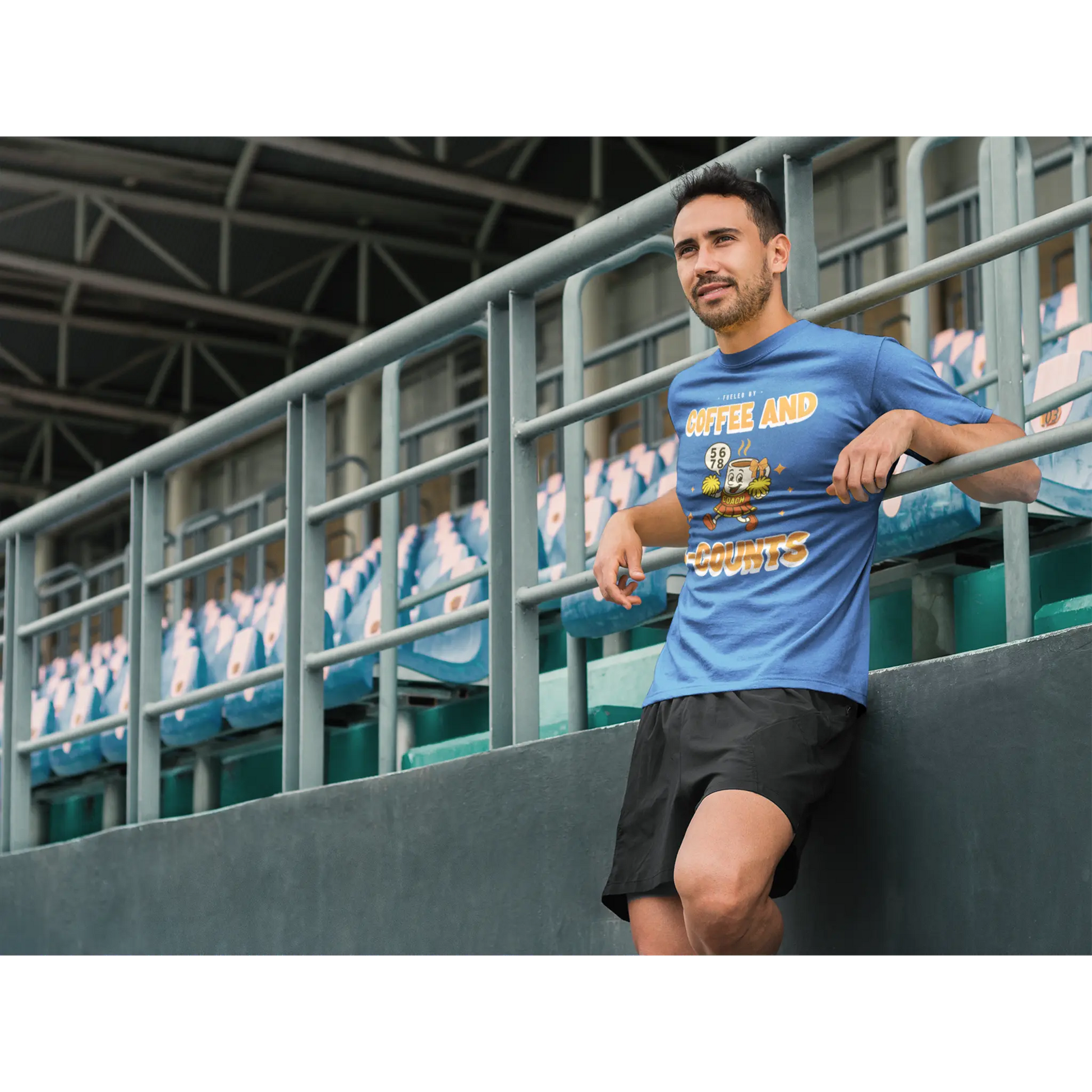 Male Cheerleading coach wearing a blue t-shirt with a cheerleading graphic design in a football stand