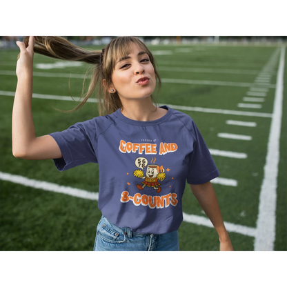 Cheerleading coach wearing a navy t-shirt with a cheerleading graphic design on a football field