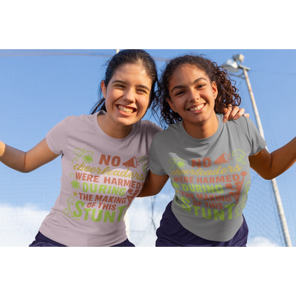 Two girls wearing t-shirts with humorous cheerleading text against a clear blue sky.